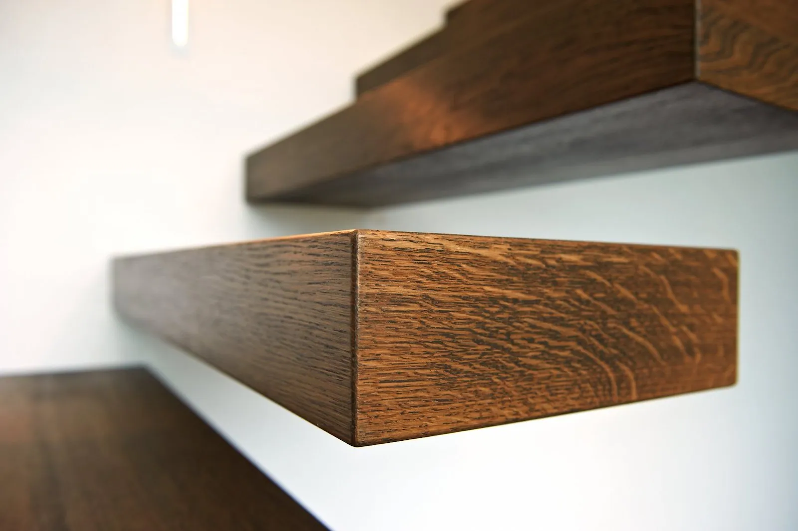 Detail van een zwevende trede in massief hout en haar verborgen verankering